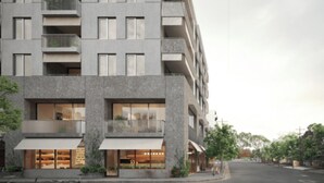 Ein modernes, mehrstöckiges Gebäude mit Balkonen und großen Fenstern, vor der Fassade ein Fahrrad abgestellt.
