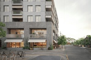 Un immeuble moderne à plusieurs étages, doté de balcons, de grandes fenêtres et d’un vélo garé devant.