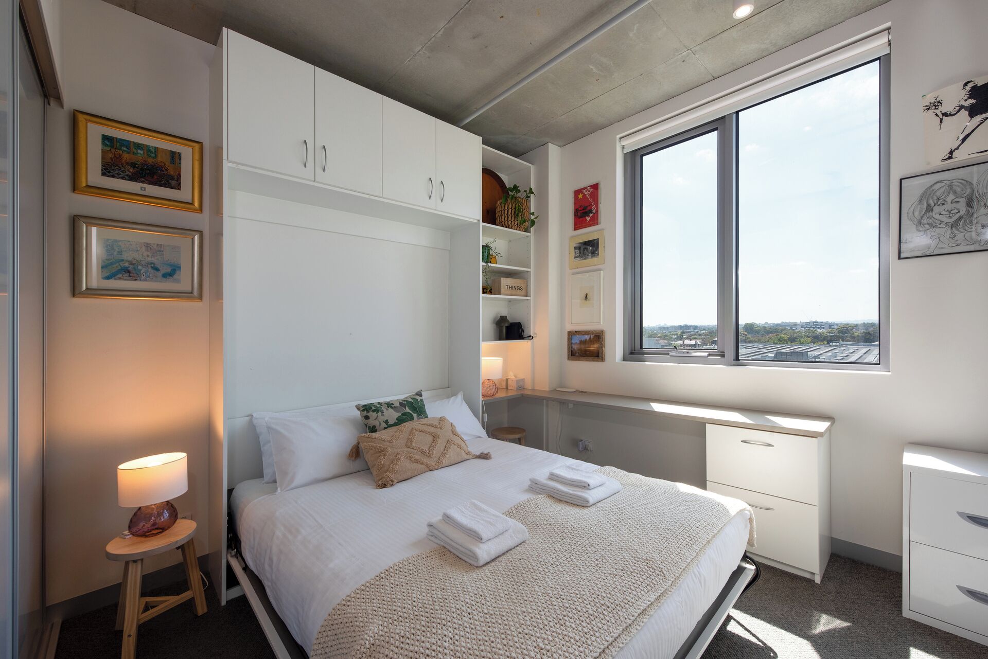 Un dormitorio con cama, mesita de noche, ventana y espacio de almacenamiento integrado.