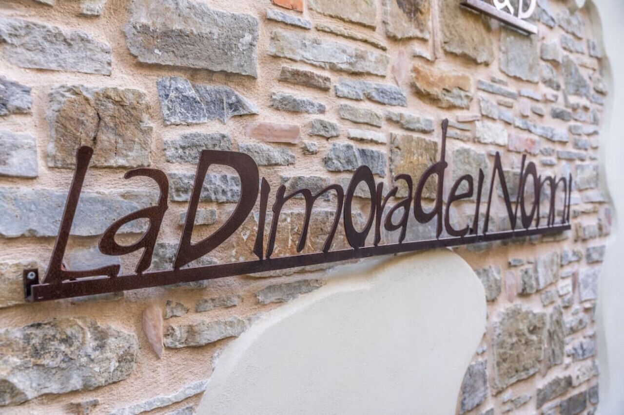 Ein Metallschild mit der Aufschrift 'La Dimoradela Normana', angebracht an einer Steinmauer.