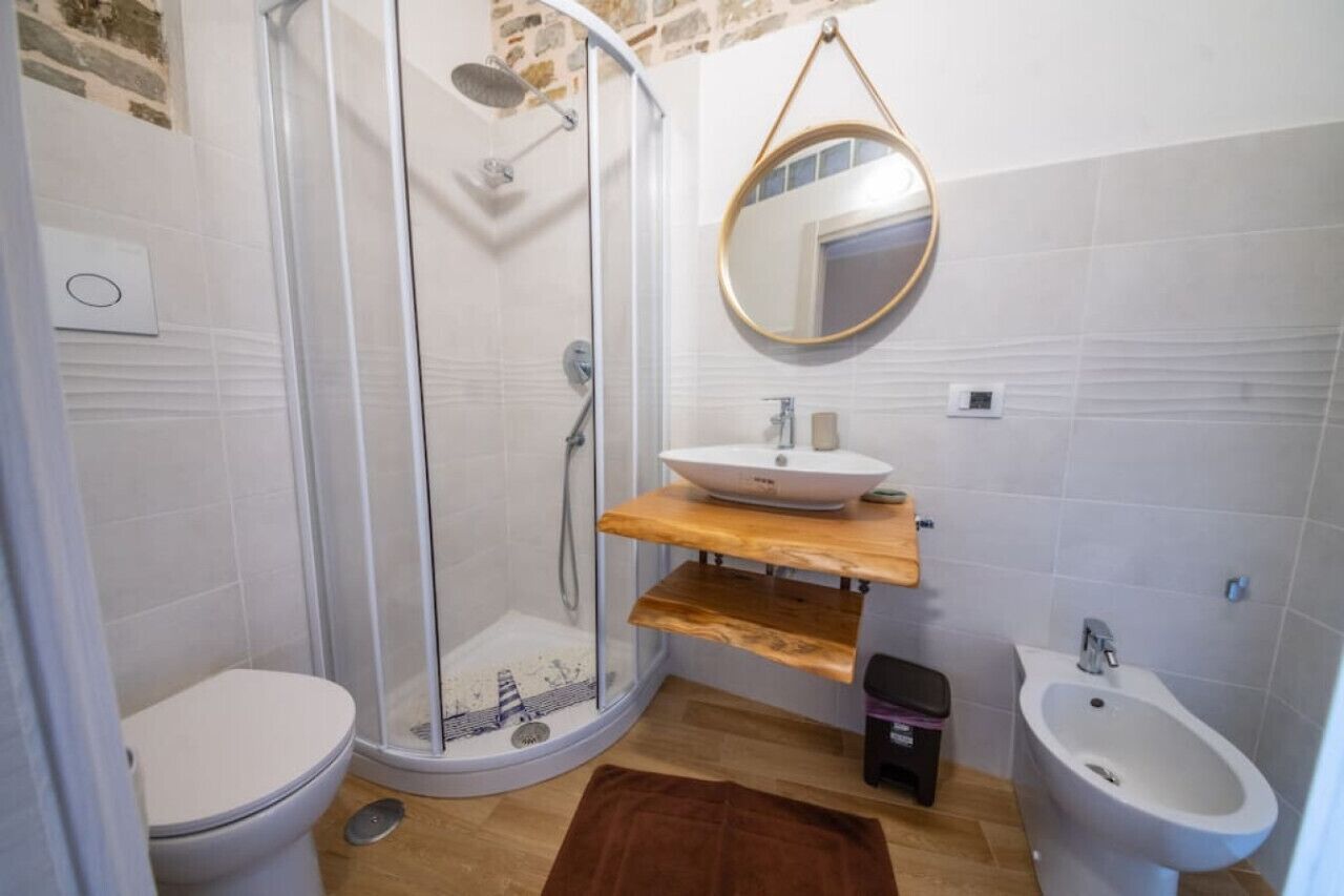 A bathroom with a glass-enclosed shower, a white sink, a bidet, and a toilet.