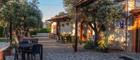 An outdoor patio area with stone flooring, tables, and chairs.