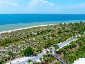 An aerial view of a coastal area with a paved walkway, a vehicle, and a beach. - Once Upon A Tide (Port St. Joe)