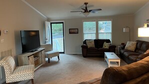 A living room with a television, two sofas, a coffee table, and a ceiling fan.