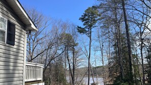A house with a porch and a driveway leading to a forested area.