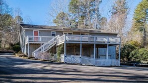 A two-story house with a front porch, a covered deck, and a staircase leading to the second floor.