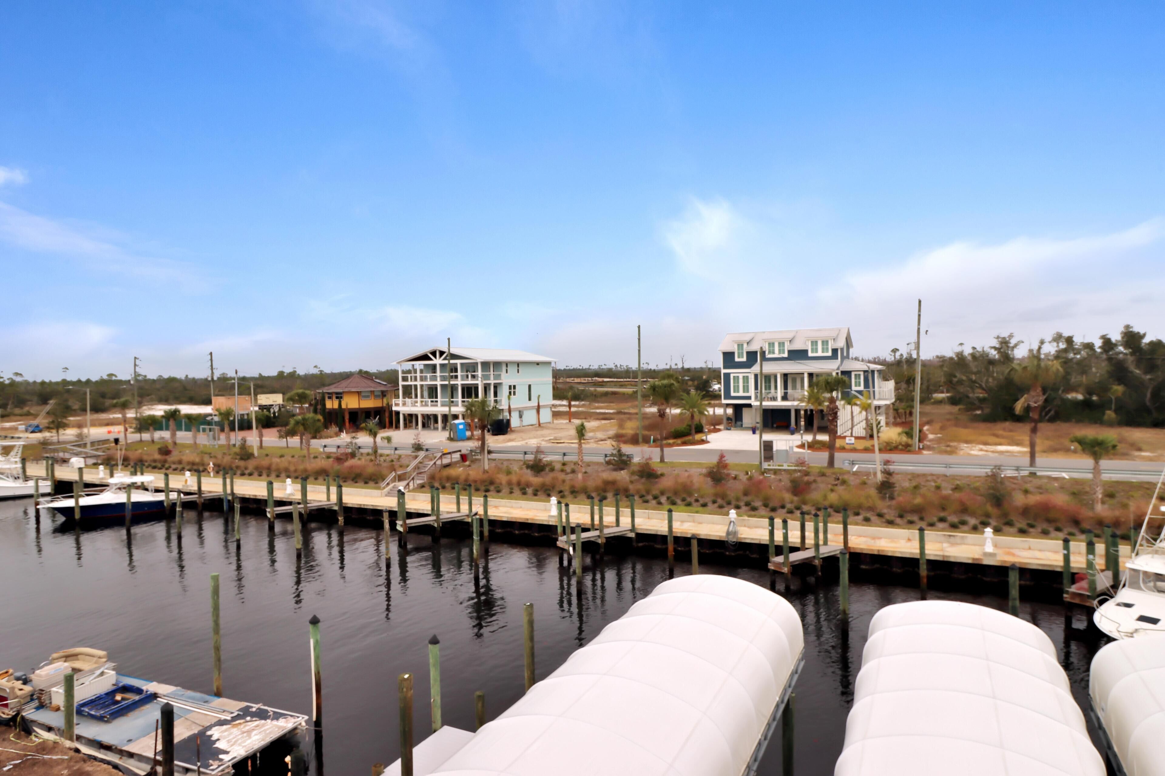 A marina with docked boats, a water tank, and two buildings in the background.
