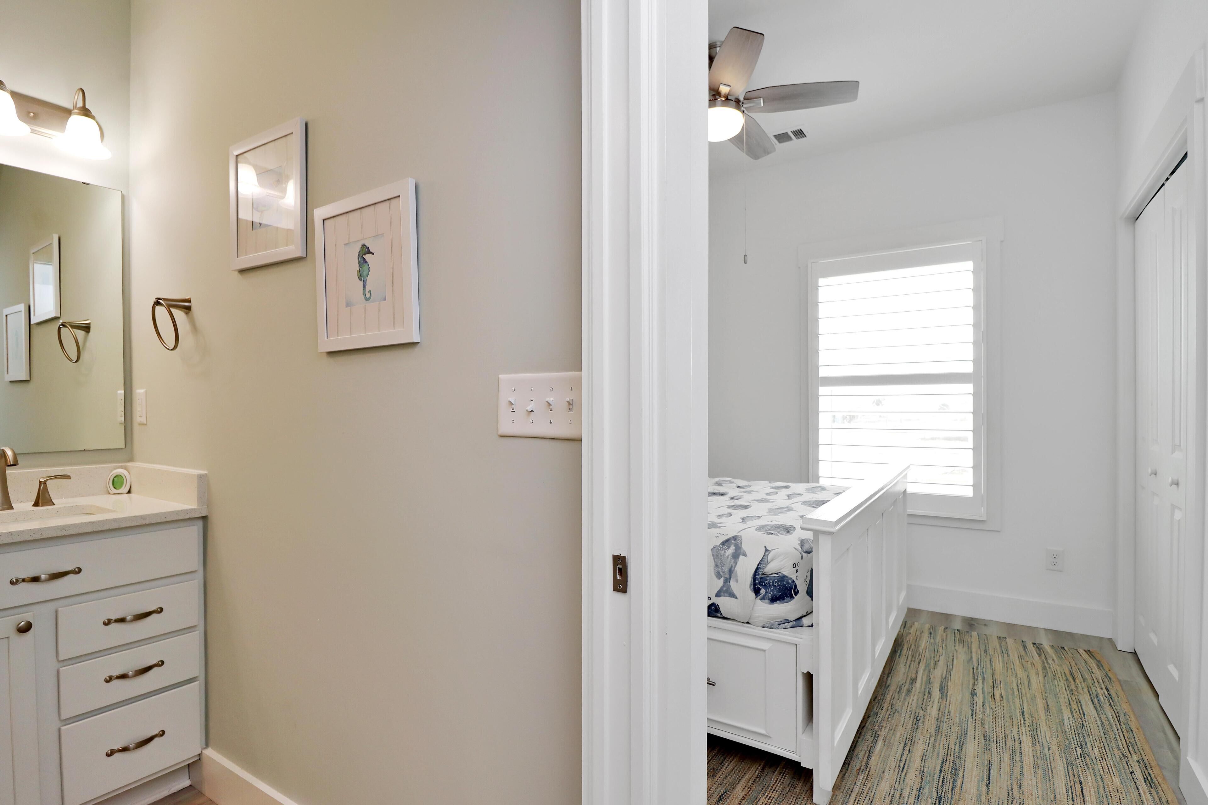 A bathroom with a sink, mirror, and framed pictures on the wall.