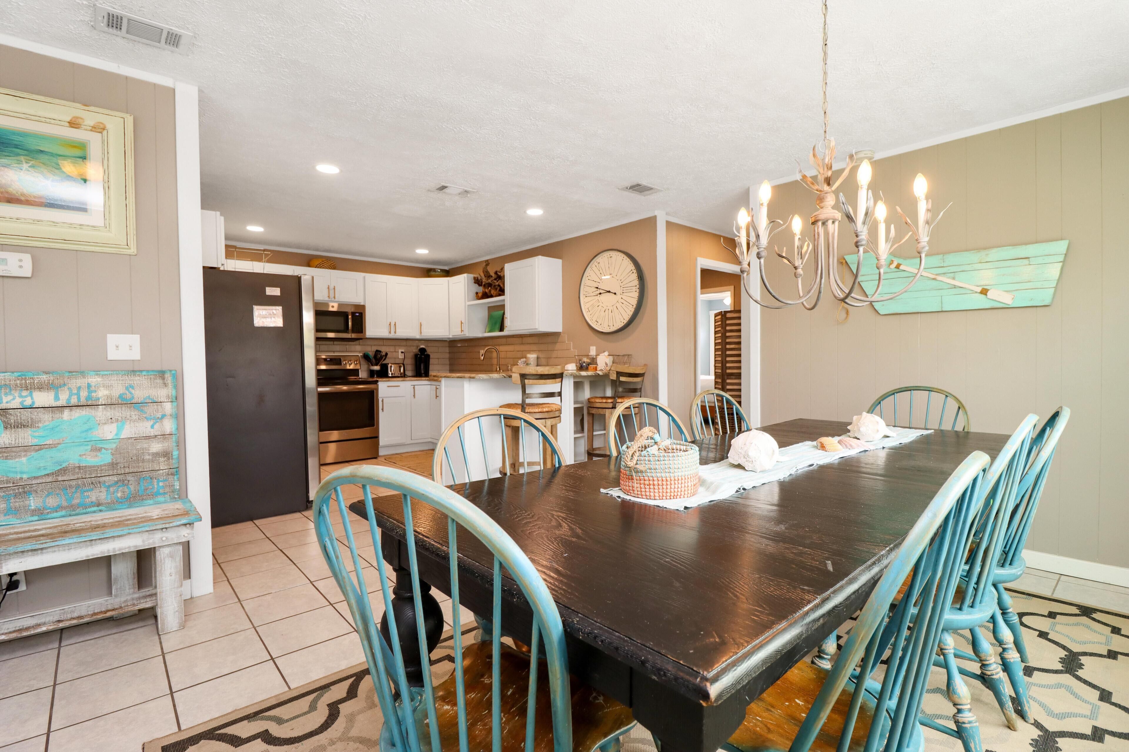Un coin repas avec une table en bois foncé, des chaises de couleur turquoise et un lustre.