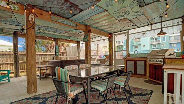 An outdoor patio with a glass-top table, striped cushioned chairs, and a patterned rug. - Castaway (Port St. Joe)