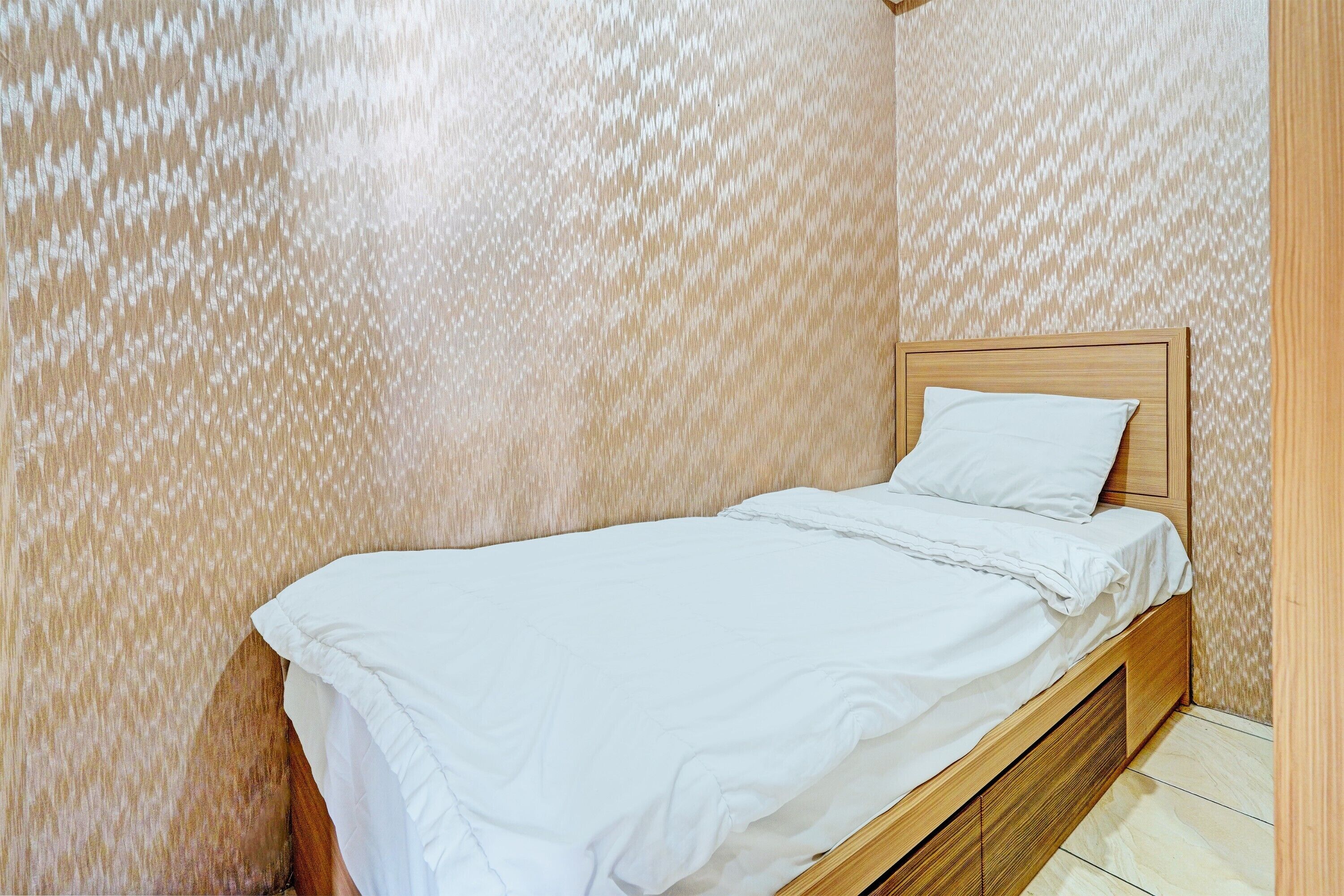 Una cama individual con cabecera de madera en una habitación con papel tapiz estampado.
