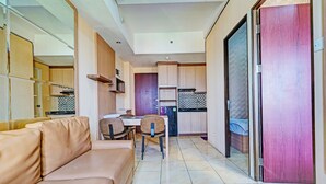 Ein modernes Wohnzimmer mit einer Couch, einem Essbereich mit Tisch und Stühlen sowie einer Küche mit Schränken und Arbeitsfläche.