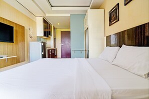 Relax in this inviting room featuring a large bed with crisp linens, a TV, and convenient kitchenette.