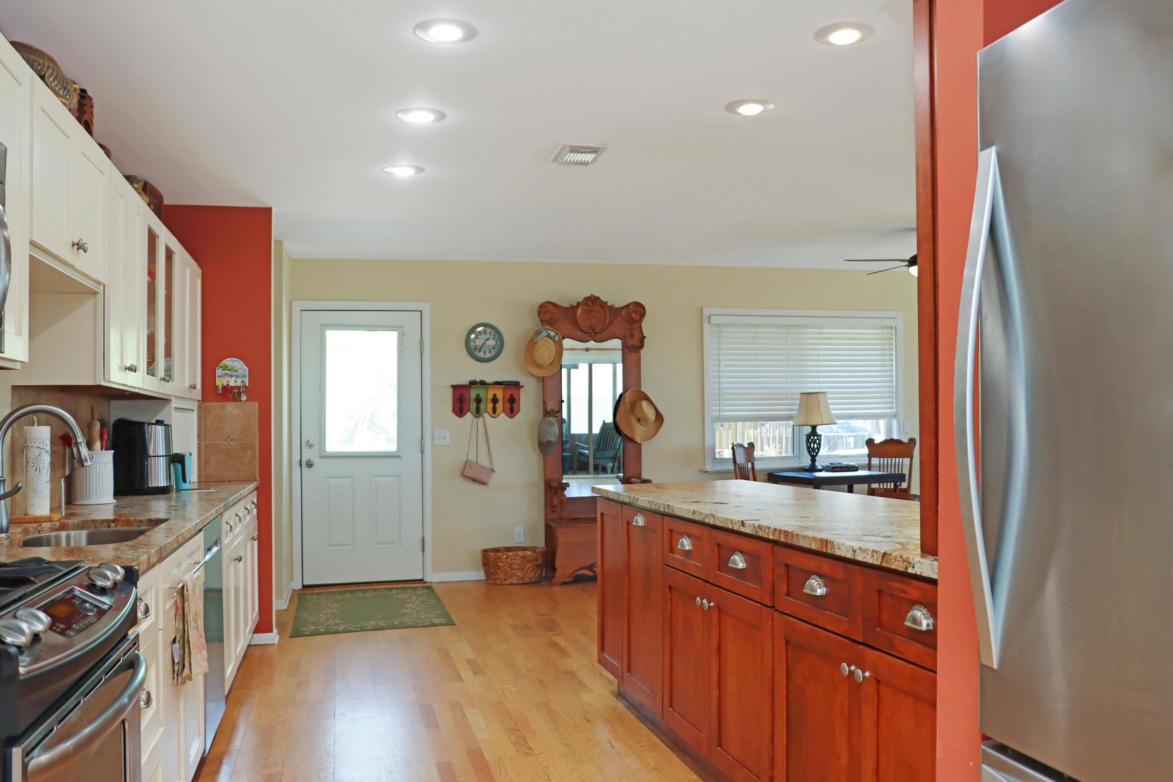 A kitchen with wooden cabinets, a stainless steel refrigerator, and a large window with blinds.