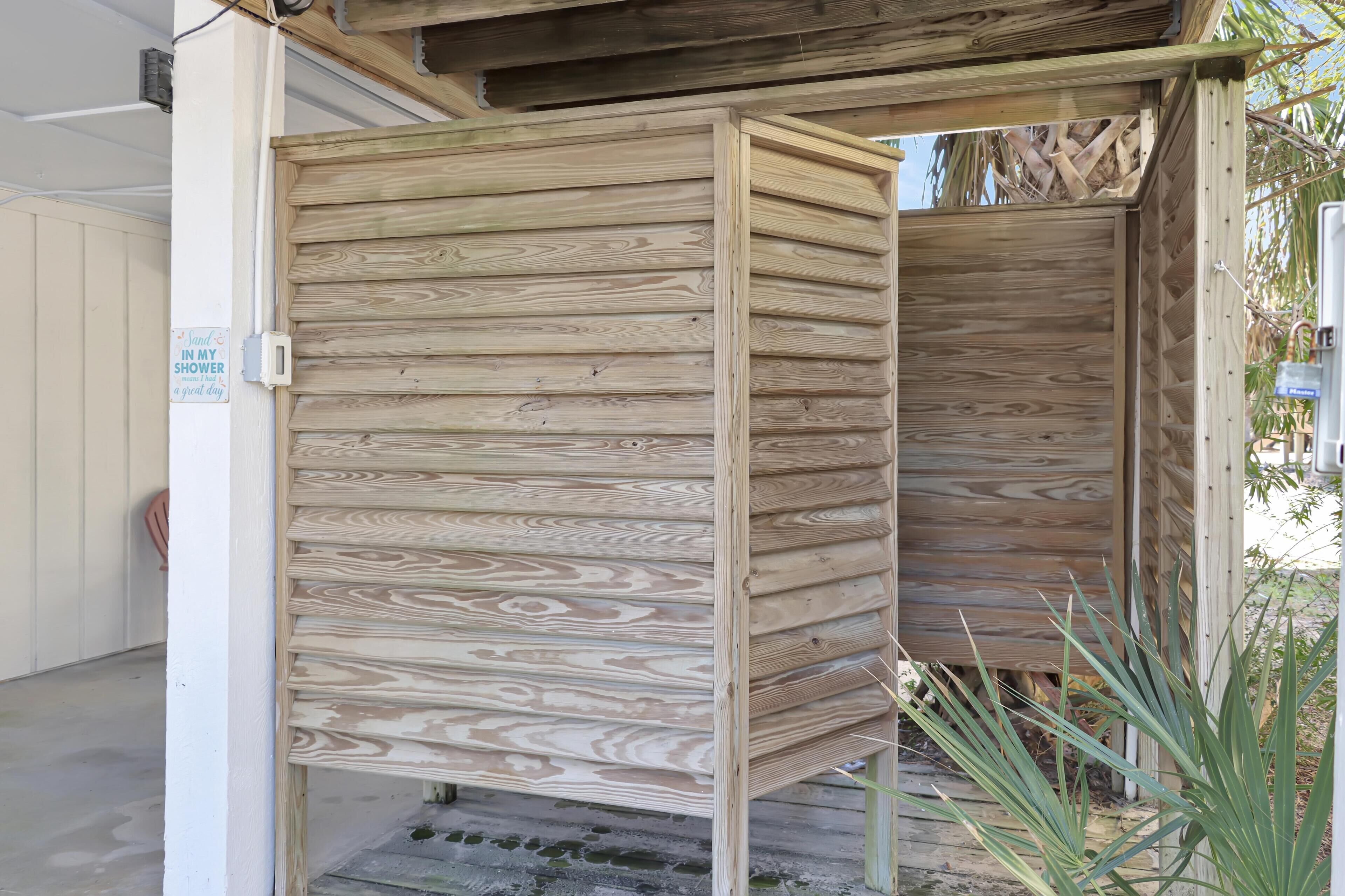 A wooden structure with a sign that reads "Shower in my shower."