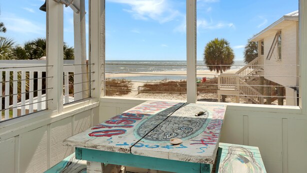 Uitzicht op het strand vanuit een kamer met een tafel waarop kunstwerken en een sterdecoratie staan.