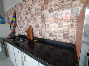 Kitchen area with a sink and black countertop, featuring a unique vintage-inspired wall design and white cabinets with silver handles.