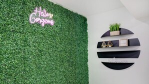 A wall with a green artificial grass texture and a neon sign that reads "Hello Gorgeous".