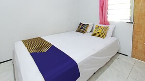 A single bed with a white mattress, blue and yellow patterned bedspread, and two decorative pillows with geometric designs. - OYO Life 92960 Rumah Kos Kita (Gangga)