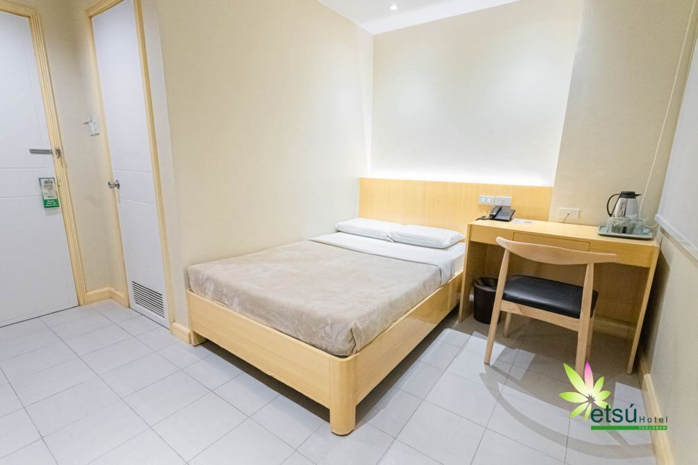 Et hotelværelse med en seng, et skrivebord og en stol.
