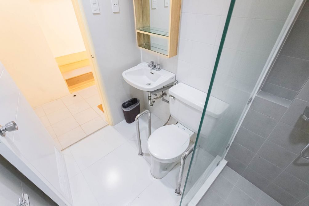 Een moderne badkamer met een glazen douchecabine, een witte wastafel en een toilet.