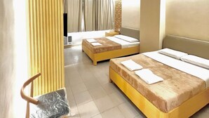 Habitación de hotel con dos camas, una silla y un ventanal con cortinas.