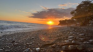 En stenstrand med solnedgang over havet.