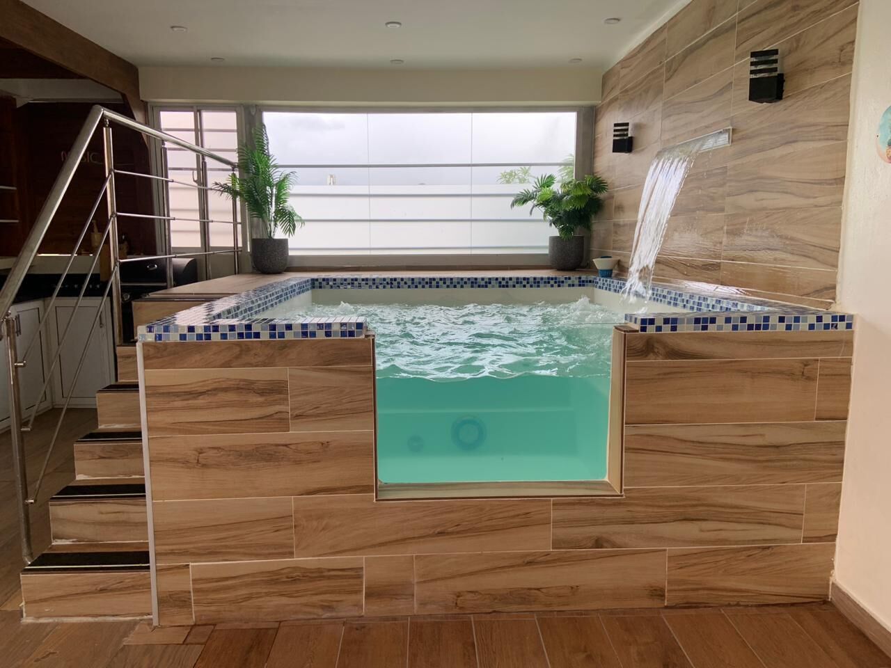 A modern indoor pool with a wooden floor and a glass barrier.