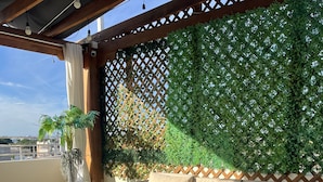 Un balcón con un sofá de mimbre, una mesita de centro y una planta en maceta.