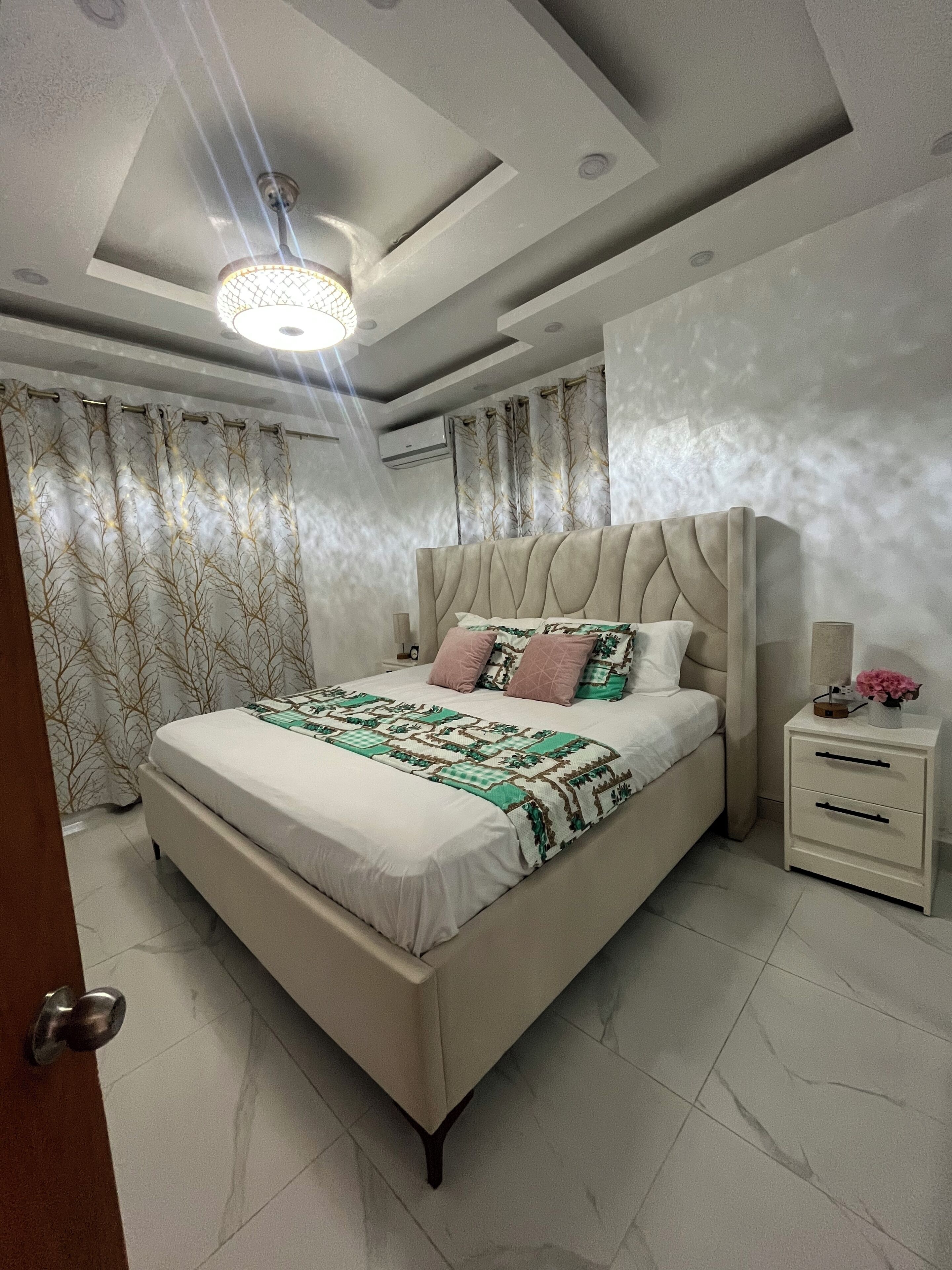 Un dormitorio moderno con una cama grande, una mesita de noche y una lámpara de techo.