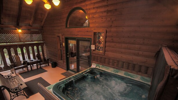 A wooden cabin interior with a hot tub, wooden benches, and a door leading outside. - NEW RIVER GORGE CABINS-ALMOST HEAVEN (Lansing)