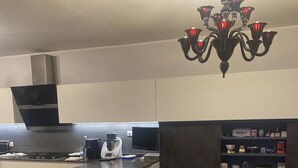 A modern kitchen with a gas stove, a coffee maker, and a microwave. There is a bar area with stools and a table with a quilted tablecloth.