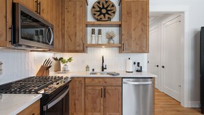 A modern kitchen with wooden cabinets, a stainless steel refrigerator, a microwave, a sink, and a dishwasher. - Holly Grove Cottage W/ Hot Tub (Vancouver)