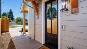 A house with a black front door, a wooden porch, and a doormat with "STAY A" written on it. - Holly Grove Cottage W/ Hot Tub (Vancouver)