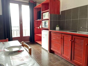 Enjoy meals in this cozy kitchen with a dining table for two, featuring a refrigerator, microwave, and potted plant.