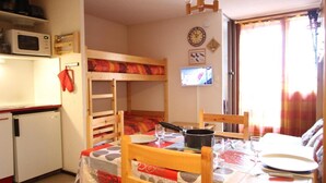 A compact kitchen with a microwave, a small refrigerator, and a wooden table set for dining. - 100m from ski slopes, Ground floor, balcony, ski locker, 24m², Chamrousse (Chamrousse)