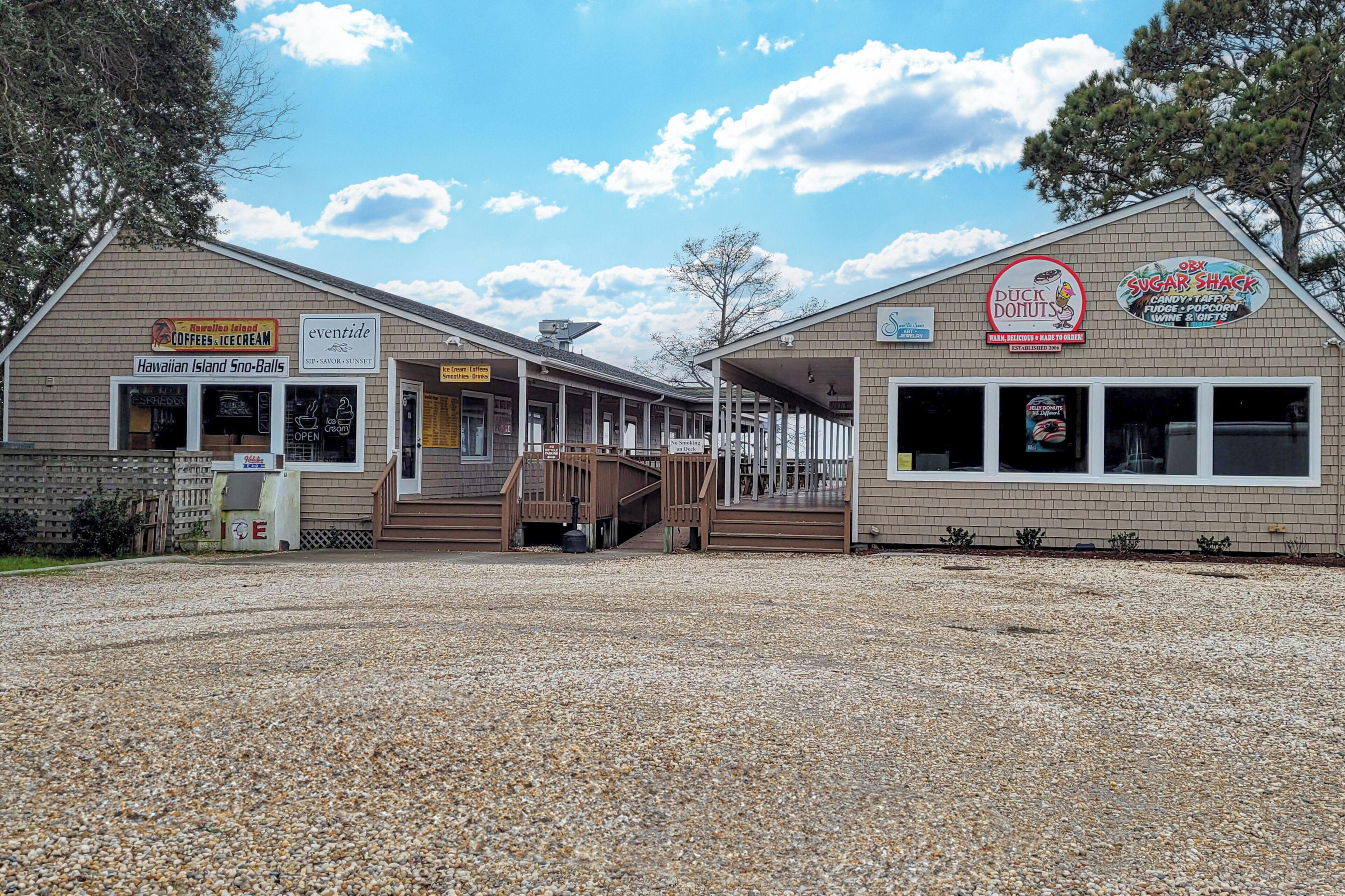 Un edificio con letreros de Hawaiian Island Sno-Balls, Eventide, Duck Donuts y Sugar Shack.