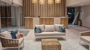A modern lobby with a sofa, wicker chairs, and a patterned rug. - Hermoso Apto en Santa Marta con Piscina (Gaira)