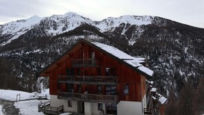 A wooden chalet with a balcony, set against a snowy mountain backdrop. - Ski-in/ski-out & foot of the slopes, 6th floor, view mountain, swimming pool, sauna, balcony, tv (Les Orres)