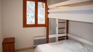 A bunk bed room with a window, radiator, and a small wooden cabinet. - Ski-in/ski-out & foot of the slopes, 6th floor, view mountain, swimming pool, sauna, balcony, tv (Les Orres)