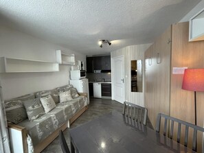 A compact living space with a sofa, dining table, kitchenette, and a small kitchen area. - 10m from ski slopes, 6th floor, balcony, tv, ski locker, 19m², Les Menuires (Les Menuires)