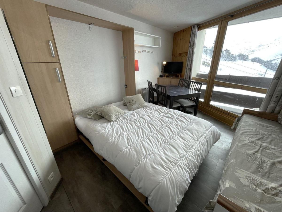 A bedroom with a bed, a desk, and a TV.
