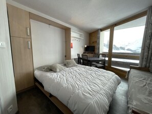A compact hotel room with a bed, a desk, and a window with a view. - 10m from ski slopes, 6th floor, balcony, tv, ski locker, 19m², Les Menuires (Les Menuires)
