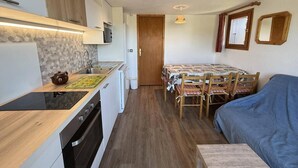 A compact kitchen with a stove, sink, and a small dining area with a table and chairs. - 100m from ski slopes, 3rd floor, view open/ski slopes, tv, ski locker, 39m², Les Saisies (Les Saisies)