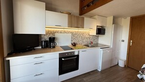 A compact kitchen with white cabinets, a microwave, a coffee maker, and a dishwasher. - 100m from ski slopes, 3rd floor, view open/ski slopes, tv, ski locker, 39m², Les Saisies (Les Saisies)