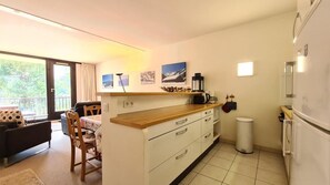 A compact kitchen with a wooden countertop, white cabinets, a built-in oven, and a refrigerator. There is a dining area with a table and chairs, and a window with curtains. - 100m from shops, 1st floor, balcony, tv, ski locker, 60m², Flaine (Flaine)