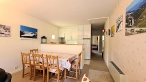 A compact kitchen with white cabinets, a dining table with chairs, and a small refrigerator. - 100m from shops, 1st floor, balcony, tv, ski locker, 60m², Flaine (Flaine)