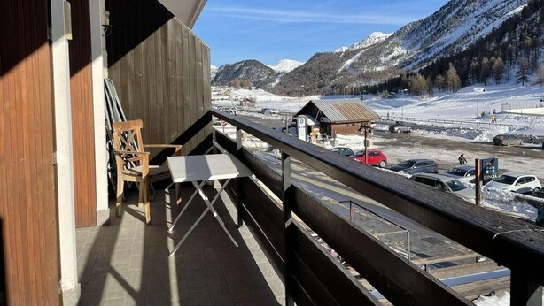 A balcony with a view of a snowy mountain landscape, a wooden chair, and a table. - 350m from resort center, 1st floor, view ski slopes, balcony, tv, 40m², Montgenèvre (Montgenèvre)