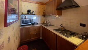 A compact kitchen with wooden cabinets, a microwave, a kettle, and a stove. - 350m from resort center, 1st floor, view ski slopes, balcony, tv, 40m², Montgenèvre (Montgenèvre)