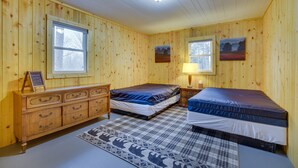 A wooden-paneled room with two beds, a dresser, and a rug. - Pet-Friendly Cabin Retreat: Wisconsin River Access (Mauston)